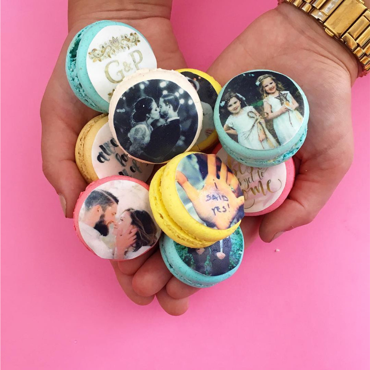 A pair of hands holding various macarons related to engagements and weddings
