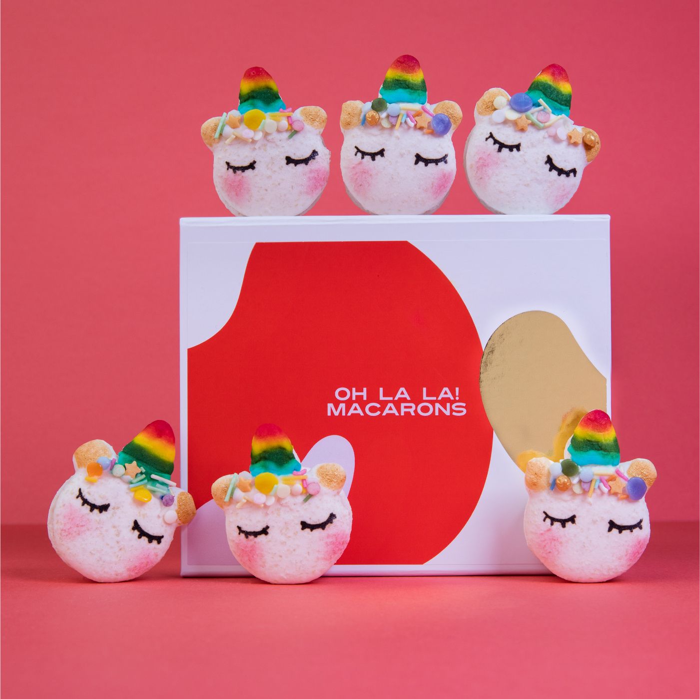 A display of white unicorn macarons with pink blush and rainbow horns
