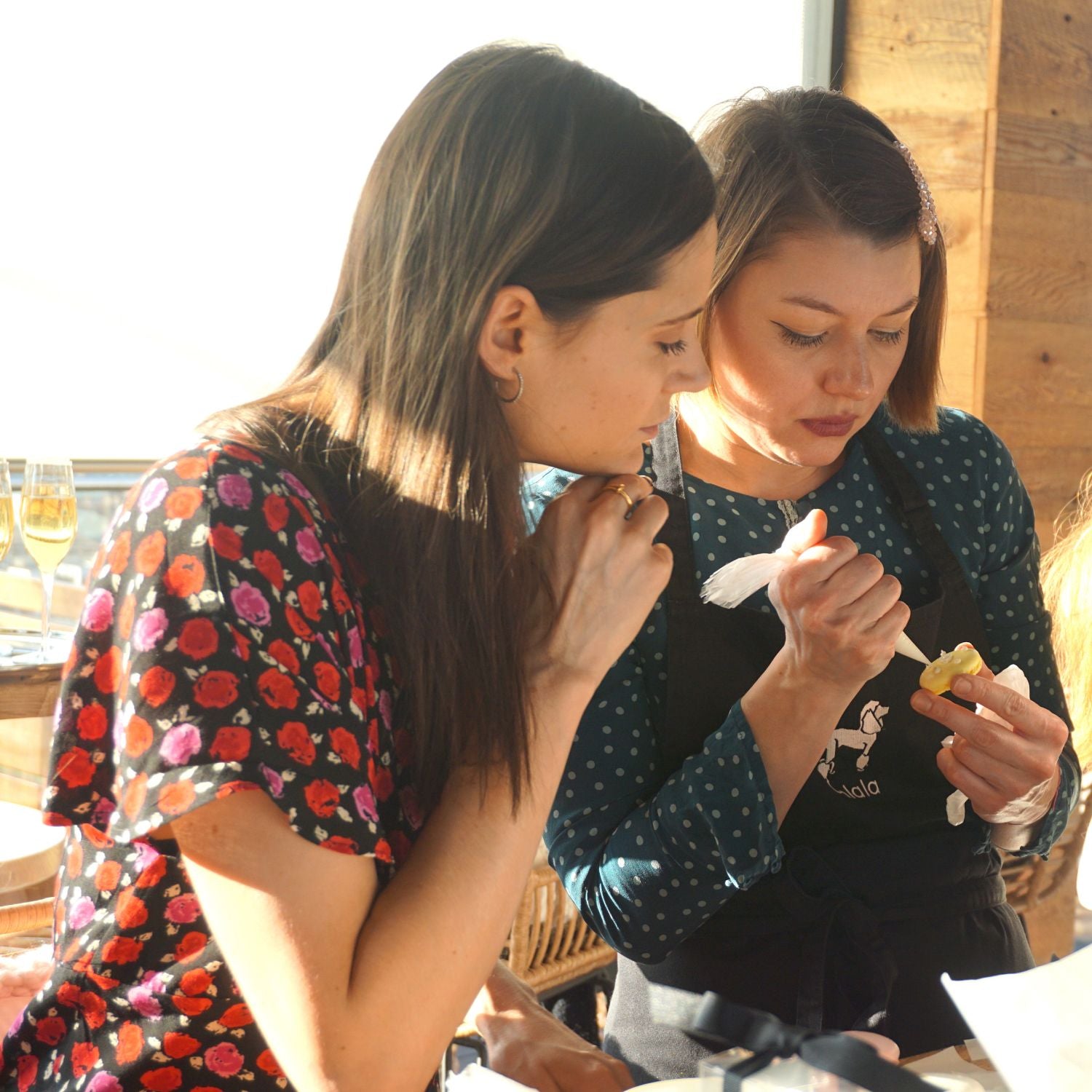 Two women decorating macarons at an Oh La La! Macarons event